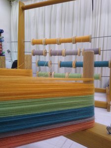 Ourdissage de la chaine de tissage d'une écharppe rayée sur cadre à ourdir.